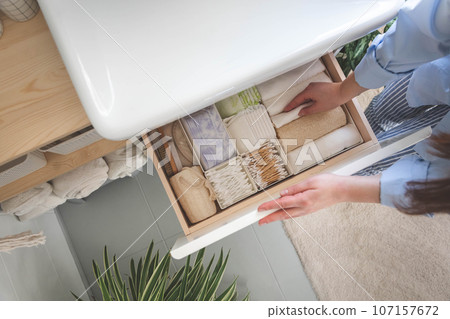 Top view of woman hands neatly organizing bathroom amenities and toiletries in drawer in bathroom. Top view of woman hands neatly organizing bathroom amenities and toiletries in drawer in bathroom. 107157672