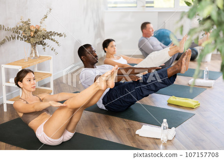 Sporty young woman performing Navasana in yoga studio 107157708