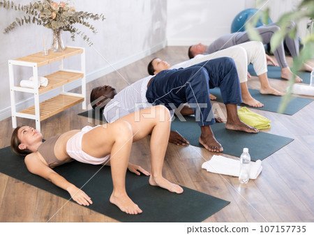 Young woman doing Setu Bandha Sarvangasana in yoga studio 107157735