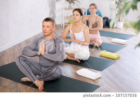 Adult man doing yoga in group in studio Adult man doing yoga in group in studio 107157838