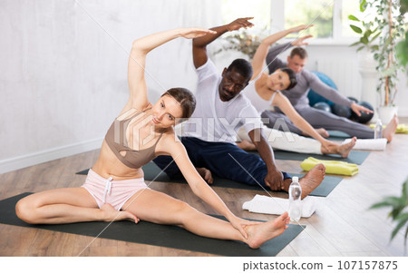 Young woman doing Parivrtta Janu Sirsasana during group yoga training 107157875