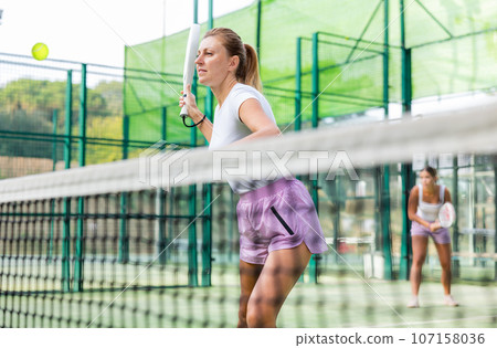 European woman padel tennis player trains on the outdoor court 107158036
