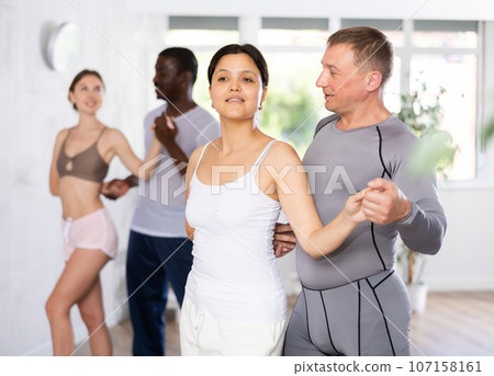 Group of multiethnic active people dancing dance movements in studio Group of multiethnic active people dancing dance movements in studio 107158161