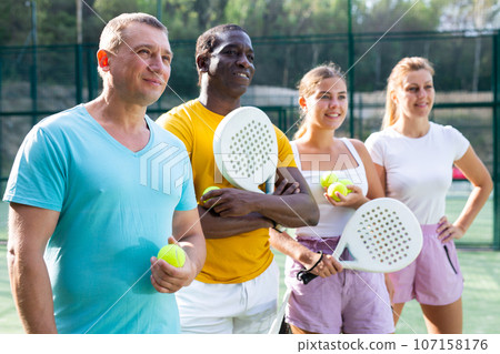 Two pairs of padel players are happily discussing past game on an open court 107158176