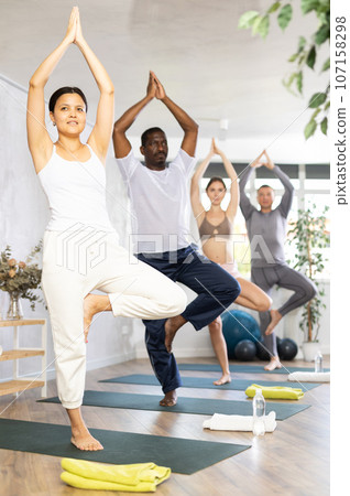 Asian woman performing balancing asana Vrikshasana in yoga studio Asian woman performing balancing asana Vrikshasana in yoga studio 107158298