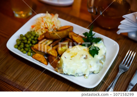 Veal Orloff with potato wedges, green peas and cabbage salad Veal Orloff with potato wedges, green peas and cabbage salad 107158299