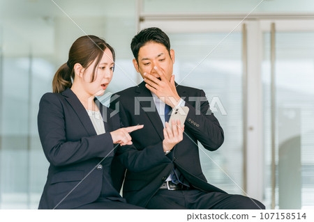 Shocked/surprised office workers looking at smartphones/smartphones (flames, troubles, failures, harassment, troubles) Shocked/surprised office workers looking at smartphones/smartphones (flames, troubles, failures, harassment, troubles) 107158514
