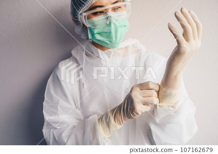 Healthcare worker wearing safety glove and PPE suit for working in hospital during Covid-19 pandemic. PPE is equipment that will protect the user against health or safety risks at work. Healthcare worker wearing safety glove and PPE suit for working in hospital during Covid-19 pandemic. PPE is equipment that will protect the user against health or safety risks at work. 107162679