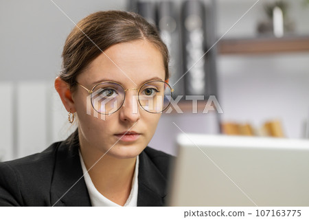 Close-up businesswoman freelancer at office workplace works on laptop computer sends online messages Close-up businesswoman freelancer at office workplace works on laptop computer sends online messages 107163775