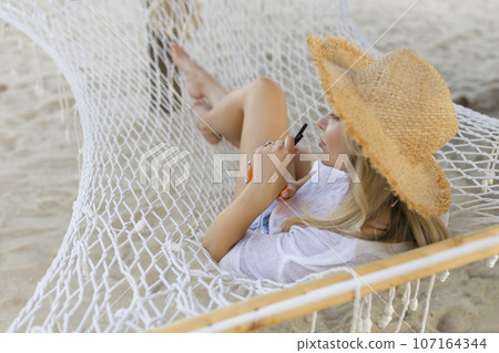 woman with cocktail relaxed in hammock 107164344