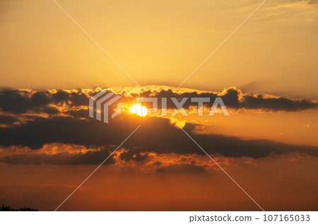Summer sunset. The setting sun in a cloudy sky background Summer sunset. The setting sun in a cloudy sky background 107165033