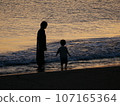 父母和孩子在日落海中玩耍 107165364