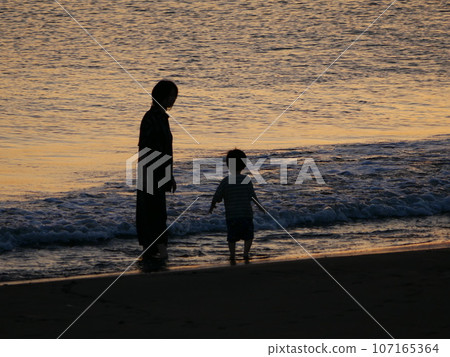 父母和孩子在日落海中玩耍 107165364