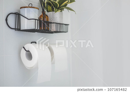Rolls of paper in the toilet, flower, diffuser of black and white flowers. Against the background of a white wall. Rolls of paper in the toilet, flower, diffuser of black and white flowers. Against the background of a white wall. 107165482