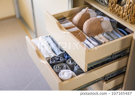 Modern wardrobe with stylish women's clothing. Drawer with underwear, t-shirts, socks and shorts. The concept of storage and order. 107165487