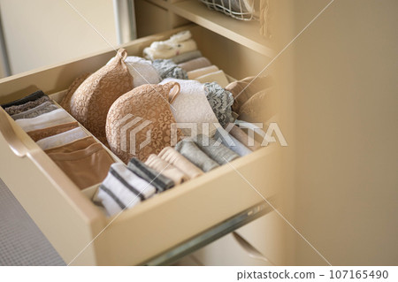 Modern wardrobe with stylish women's clothing. Drawer with underwear, t-shirts, socks and shorts. The concept of storage and order. 107165490