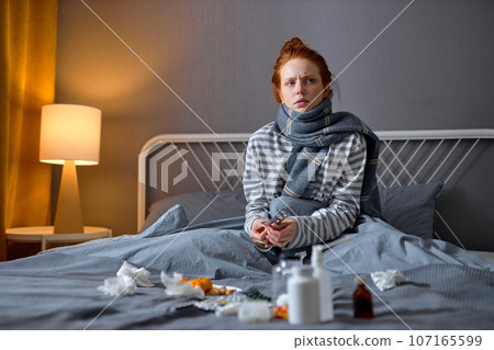serious pensive unhealthy redhead girl sitting in bedroom serious pensive unhealthy redhead girl sitting in bedroom 107165599