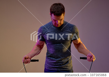 Muscular strong man holding skipping rope. 107165868