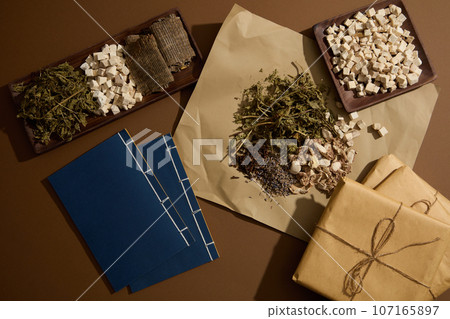 A paper and two wooden plates featured Dried mint leaves, Poria cocos and Eucommia bark. Traditional medicine to reduce inflammation and boost immunity A paper and two wooden plates featured Dried mint leaves, Poria cocos and Eucommia bark. Traditional medicine to reduce inflammation and boost immunity 107165897