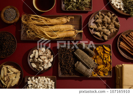 The red background featured a lot of traditional herbal medicine types placed on wooden dishes. A tonic bowl displayed. For medicine advertising with top view The red background featured a lot of traditional herbal medicine types placed on wooden dishes. A tonic bowl displayed. For medicine advertising with top view 107165910