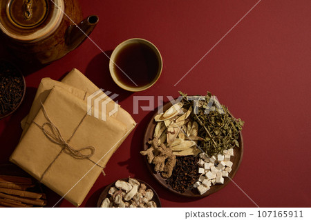 A bowl filled with tonic arranged with an earthen pot, packs of medicine and some wooden dishes containing several types of traditional Chinese medicine. Copy space. Blank space for mockup A bowl filled with tonic arranged with an earthen pot, packs of medicine and some wooden dishes containing several types of traditional Chinese medicine. Copy space. Blank space for mockup 107165911