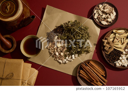 Dried mint, Poria cocos, Sand ginger, Lavender and Cloves placed on a paper. Earthen pot, a bowl of tonic displayed with some wooden dishes containing other herbal medicine Dried mint, Poria cocos, Sand ginger, Lavender and Cloves placed on a paper. Earthen pot, a bowl of tonic displayed with some wooden dishes containing other herbal medicine 107165912
