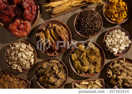 Top view of a table featured a lot of types of traditional Chinese medicine placed on many wooden dishes. Herbs are good for health and can enhance health condition Top view of a table featured a lot of types of traditional Chinese medicine placed on many wooden dishes. Herbs are good for health and can enhance health condition 107165914
