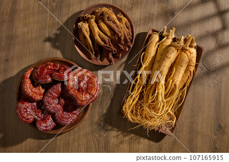 Wooden dishes in rectangle and round shape featured Red ginseng, Lingzhi mushroom and Ginseng roots. Traditional medicine content Wooden dishes in rectangle and round shape featured Red ginseng, Lingzhi mushroom and Ginseng roots. Traditional medicine content 107165915
