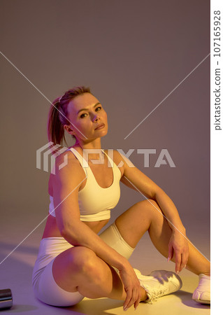 Beautiful sweaty blonde woman Relaxing on Floor Near dumbbells , tired girl Resting After Pilates Training Beautiful sweaty blonde woman Relaxing on Floor Near dumbbells , tired girl Resting After Pilates Training 107165928