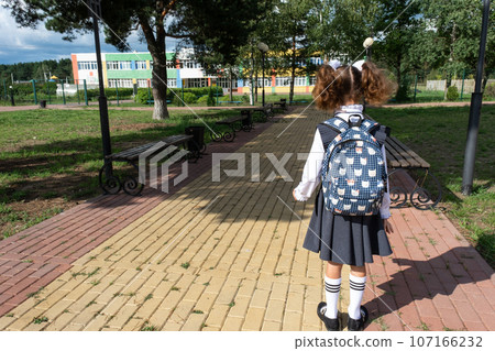 Pupil with backpack and in a school uniform in school yard back to the frame. Back to school, September 1. A happy student. Primary education, elementary class. Road to life, to knowledge Pupil with backpack and in a school uniform in school yard back to the frame. Back to school, September 1. A happy student. Primary education, elementary class. Road to life, to knowledge 107166232