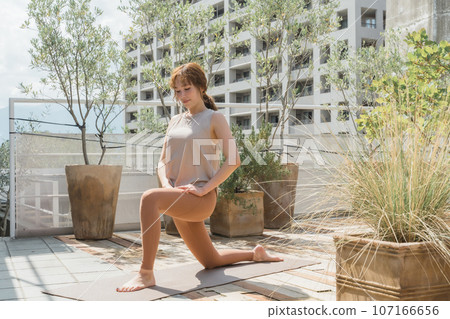 一位女士在城裡一間公寓的屋頂上做瑜珈和普拉提 一位女士在城裡一間公寓的屋頂上做瑜珈和普拉提 107166656