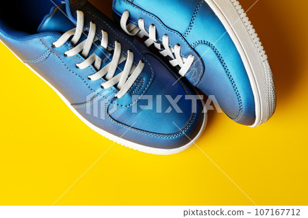 Blue new sneakers on yellow studio background Blue new sneakers on yellow studio background 107167712