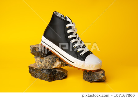 New black and white canvas sneakers on yellow background 107167800