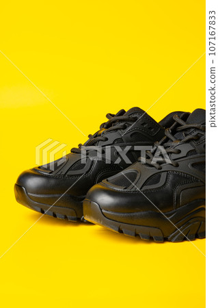Black new sport sneakers on yellow background 107167833