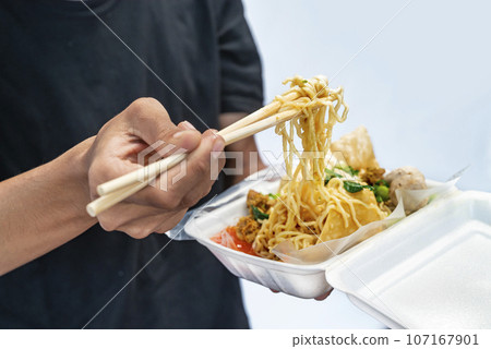 A human hand holding chicken noodles (mie ayam) 107167901