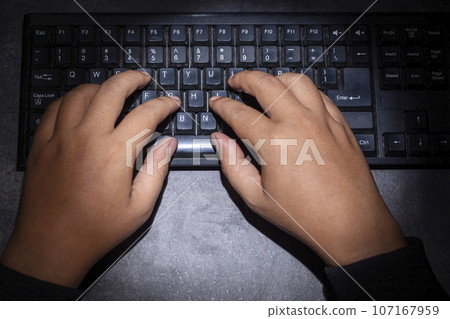 Hacker hand typing on a computer keyboard 107167959