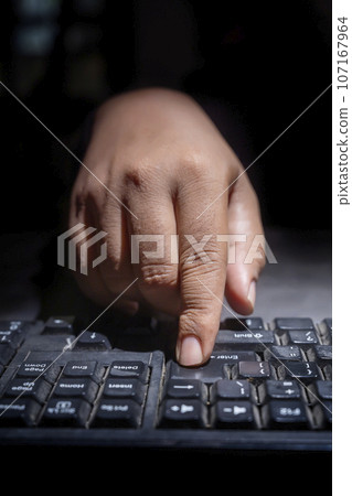 Hacker hand typing on a computer keyboard 107167964