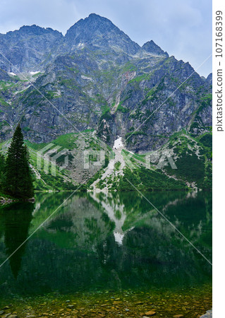 Amazing view on mountains range near beautiful lake at summer day. Tatra National Park in Poland. Panoramic view on Morskie Oko or Sea Eye lake in Five lakes valley 107168399