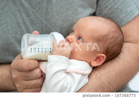 New father's experience, man holding his baby, offering formula milk with care New father's experience, man holding his baby, offering formula milk with care 107168773