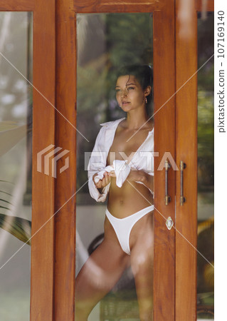 Dressing Up Young Sexy Woman in Lingerie Through Window Glass 107169140