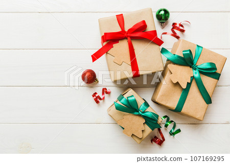 wrapped christmas or other holiday handmade present in paper with colored ribbon. Present box, decoration of gift on colourfull table, top view with copy space wrapped christmas or other holiday handmade present in paper with colored ribbon. Present box, decoration of gift on colourfull table, top view with copy space 107169295