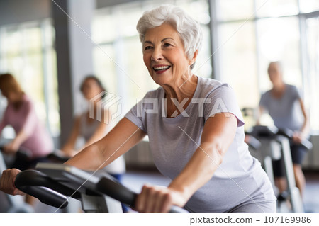 Portrait of senior woman training on stationary bike workout in gym. Concept senior active lifestyle. Generative Ai 107169986