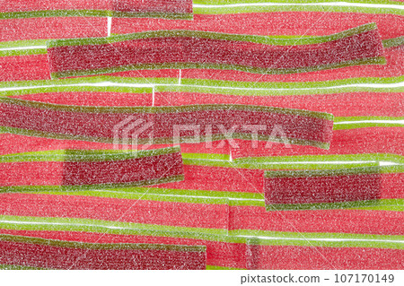 Texture of the marmalade strips laid out in rows of bright red-green colors, sprinkled with sugar. 107170149