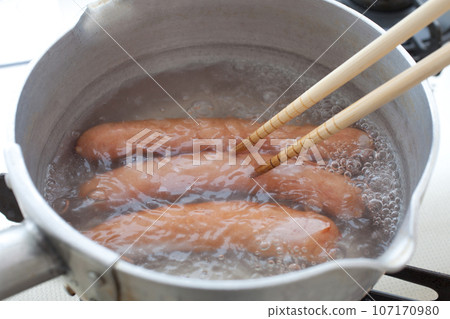 Scene of boiling three sausages, chopsticks included 107170980