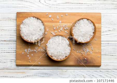 A wooden bowl of salt crystals on a wooden background. Salt in rustic bowls, top view with copy space A wooden bowl of salt crystals on a wooden background. Salt in rustic bowls, top view with copy space 107171446