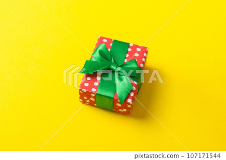 Wrapped christmas or other holiday handmade present in paper with colored ribbon. Present box, decoration of gift on table, top view with copy space Wrapped christmas or other holiday handmade present in paper with colored ribbon. Present box, decoration of gift on table, top view with copy space 107171544