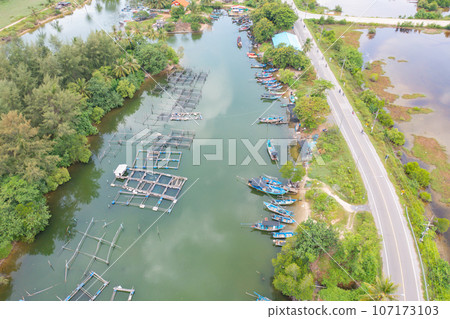 Aerial view of fishing trap net in canel with fisherman urban city village town houses, lake or river. Nature landscape fisheries and fishing tools at Pak Pha, Songkhla, Thailand. Aquaculture farming 107173103