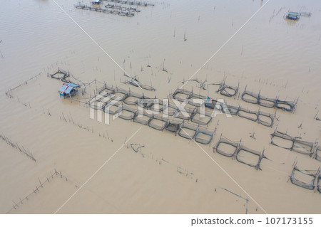 Aerial view of fishing trap net in canel with fisherman urban city village town houses, lake or river. Nature landscape fisheries and fishing tools at Pak Pha, Songkhla, Thailand. Aquaculture farming 107173155