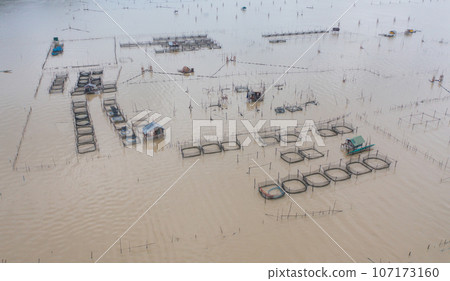 Aerial view of fishing trap net in canel with fisherman urban city village town houses, lake or river. Nature landscape fisheries and fishing tools at Pak Pha, Songkhla, Thailand. Aquaculture farming 107173160