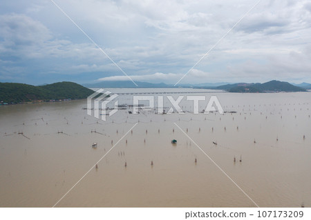 Aerial view of fishing trap net in canel with fisherman urban city village town houses, lake or river. Nature landscape fisheries and fishing tools at Pak Pha, Songkhla, Thailand. Aquaculture farming 107173209